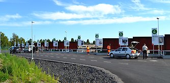 Bilden visar rampen på Kretsloppsparken med några få bilar och personer som slänger avfall vid containrarna.